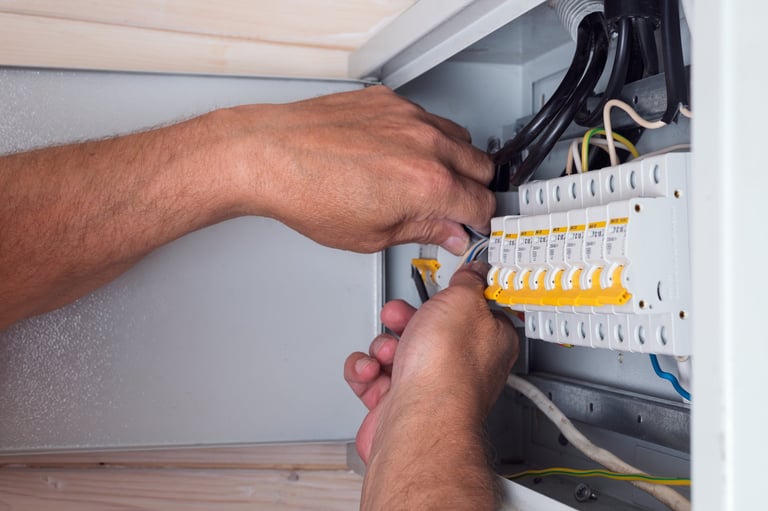 Electrician connecting cables in distribution board